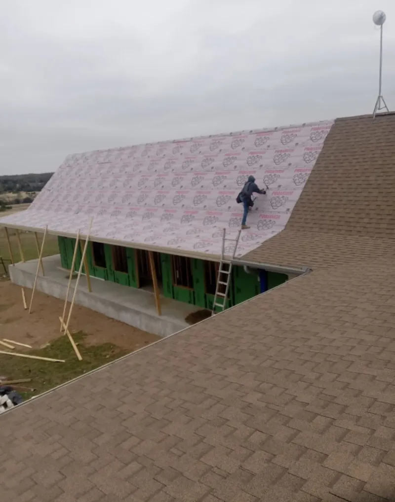 Worker preparing underlayment for a metal roof installation in Point Pleasant